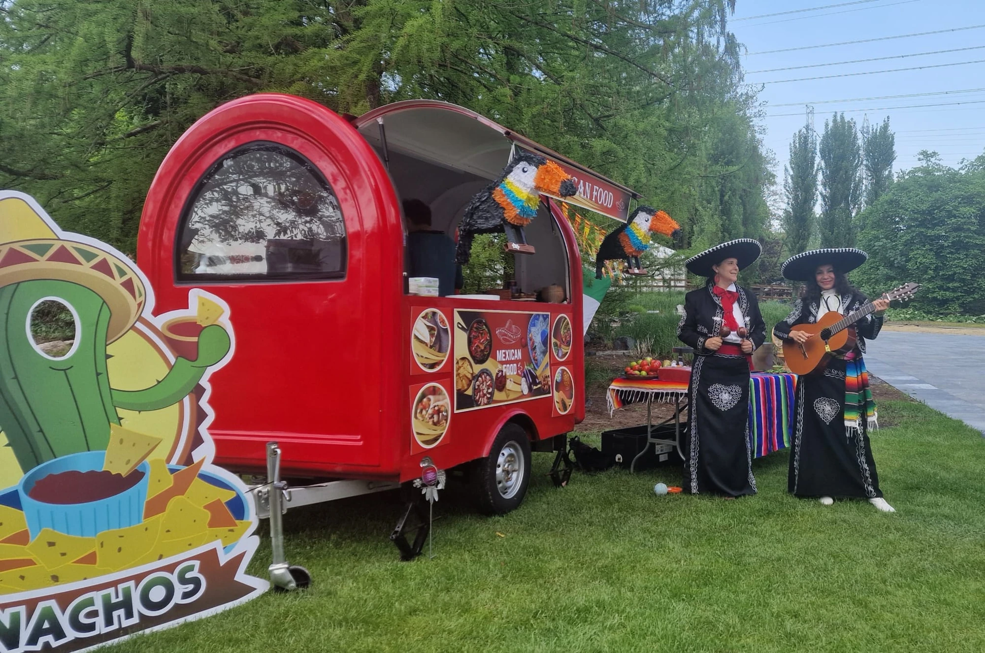 Onze rode foodtruck op een grasveld, met muzikanten ernaast
